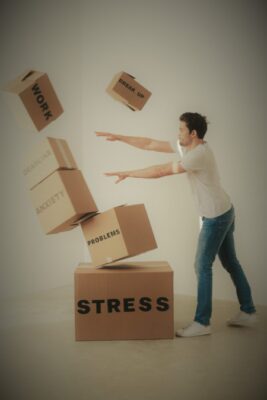 homme qui pousse une pile de cartons étiquetés stress, problèmes, anxiété, débordé par les événements de la vie